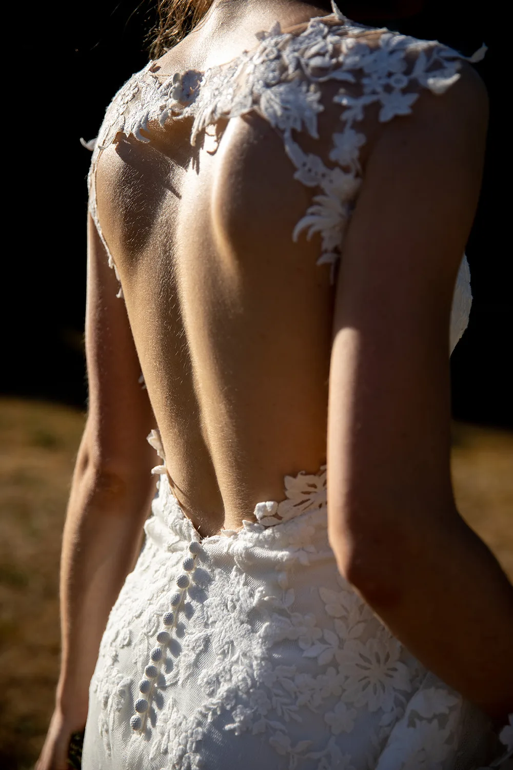 Dos de robe de mariée en dentelle dans la lumière dorée — photographe mariage Pays de Gex