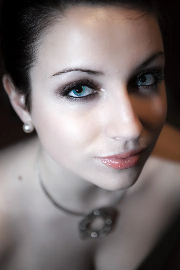 Portrait rapproché d'une femme au regard bleu intense, collier et perle — séance portrait studio