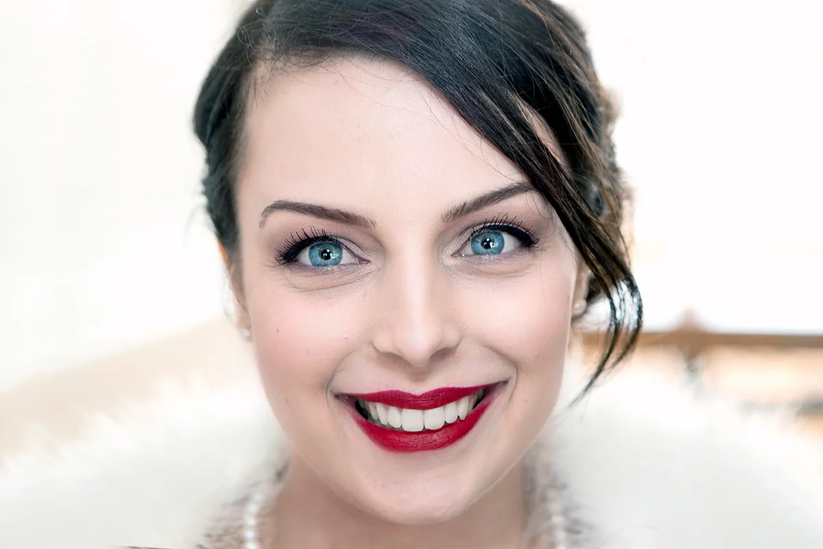 Portrait rapproché d'une femme aux yeux bleus, sourire éclatant — séance portrait en studio